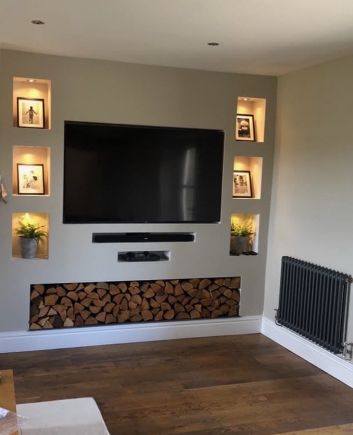 A media wall built by HDC Group, with lit alcoves and a log store